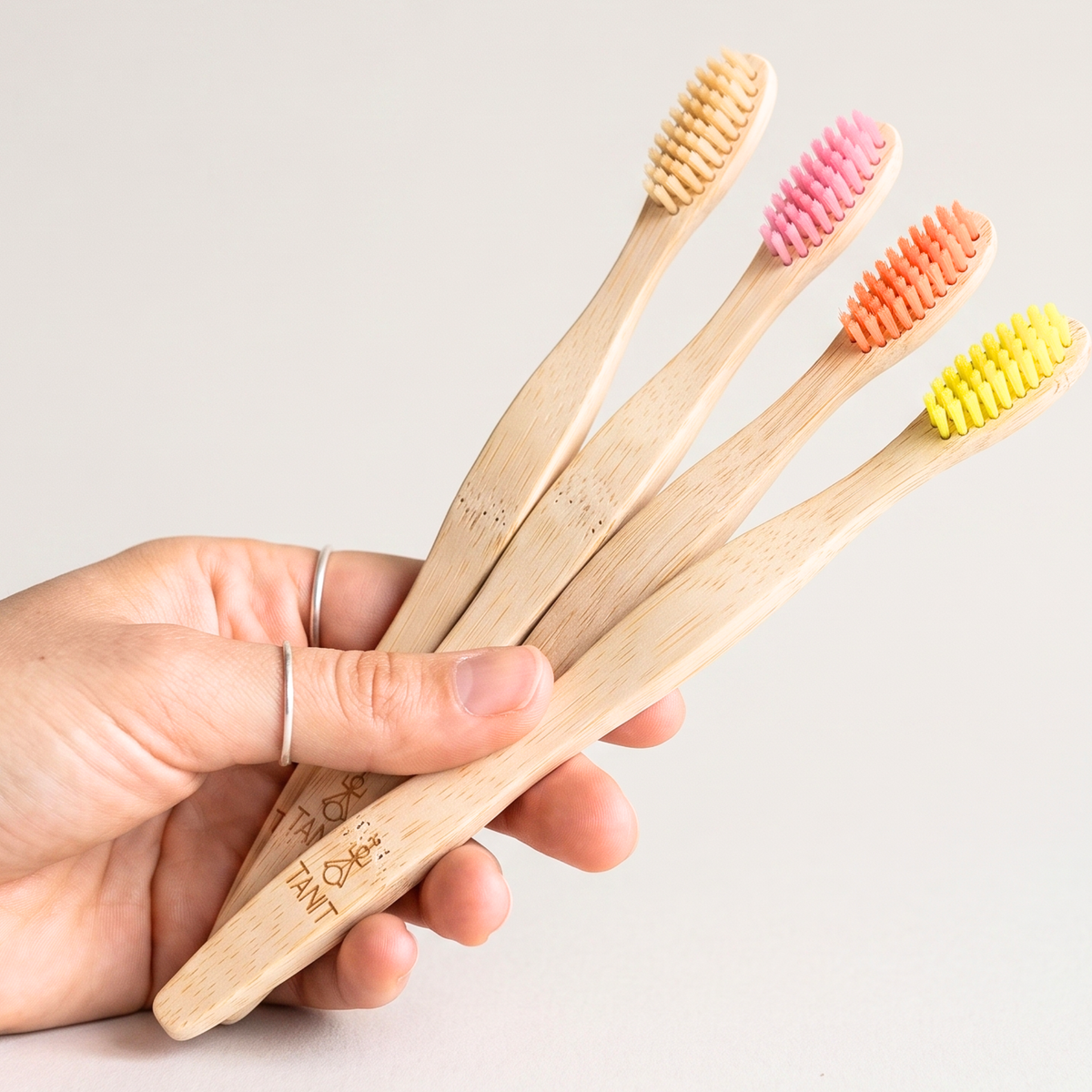 Une main tenant quatre brosses à dents en bambou TANIT pour adultes