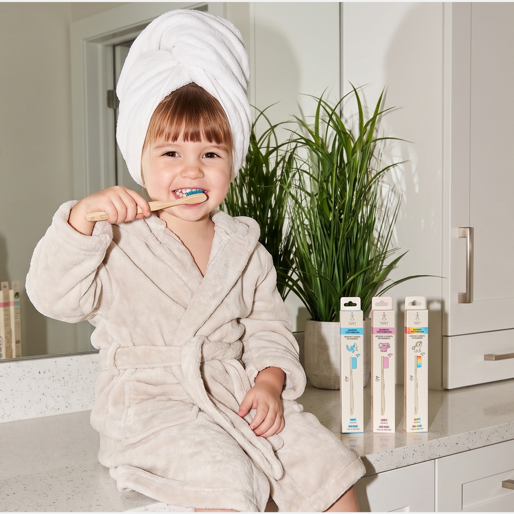 Jeune enfant en peignoir se brossant les dents avec une brosse à dents en bambou TANIT