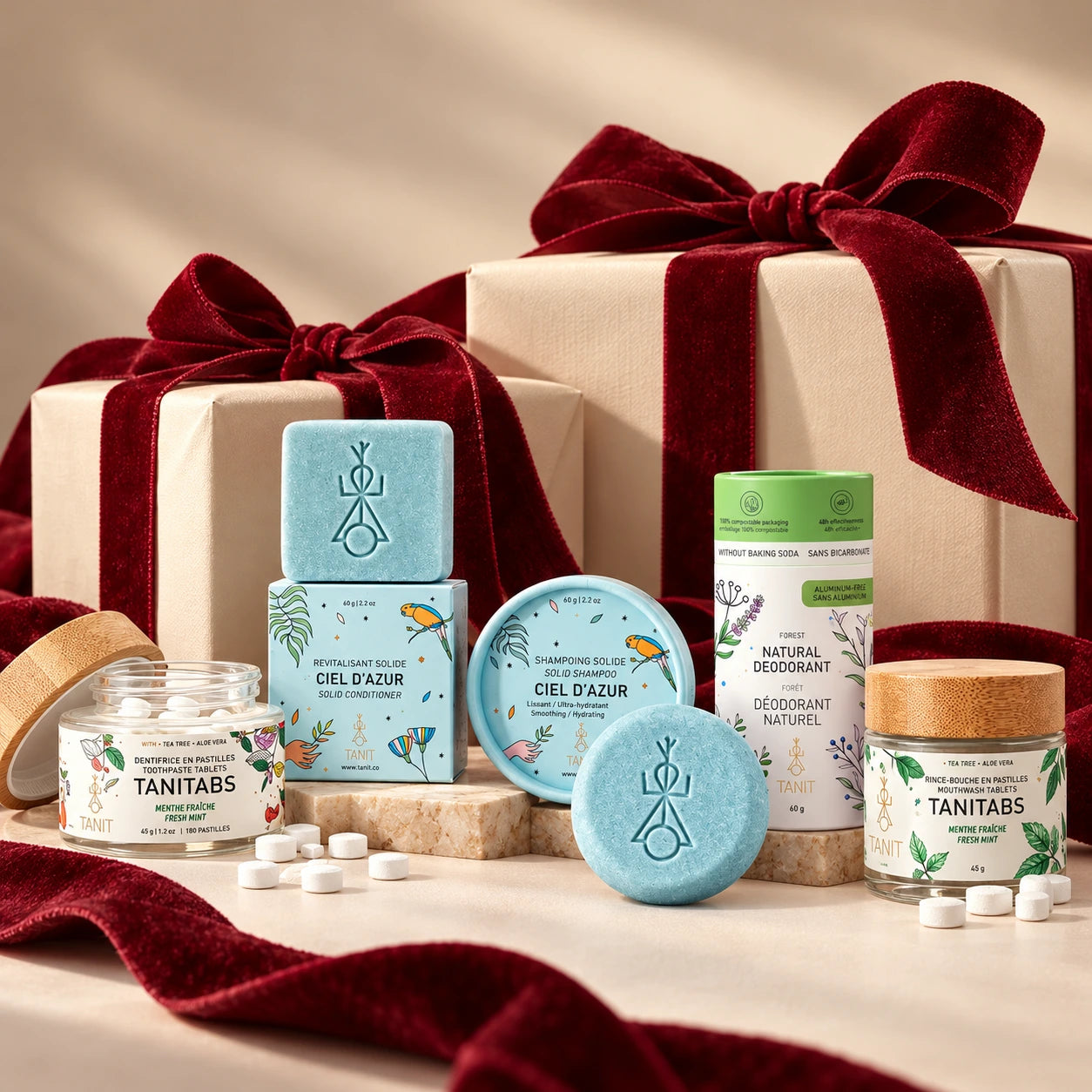 Essentiels de la routine solide TANIT entourés de cadeaux emballés crème et de boucles bourgogne